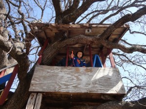 Noah waving his spring flower poem from the treehouse
